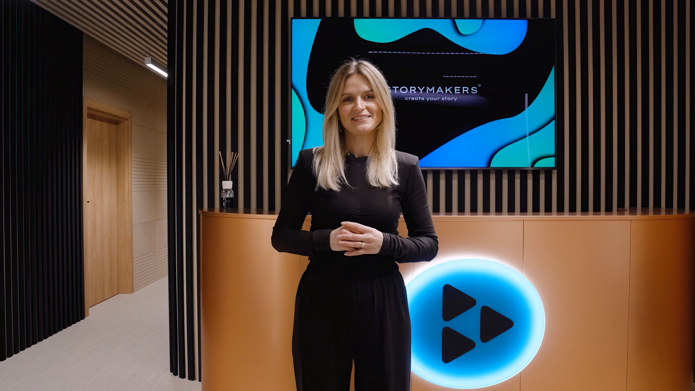 Powitanie w recepcji Storymakers Space - prowadząca przy ekranie z logo marki