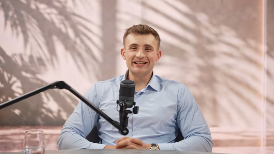 Kadr z nagrania opinii: Daniel Lalewicz w jasnoniebieskiej koszuli przy mikrofonie w studiu